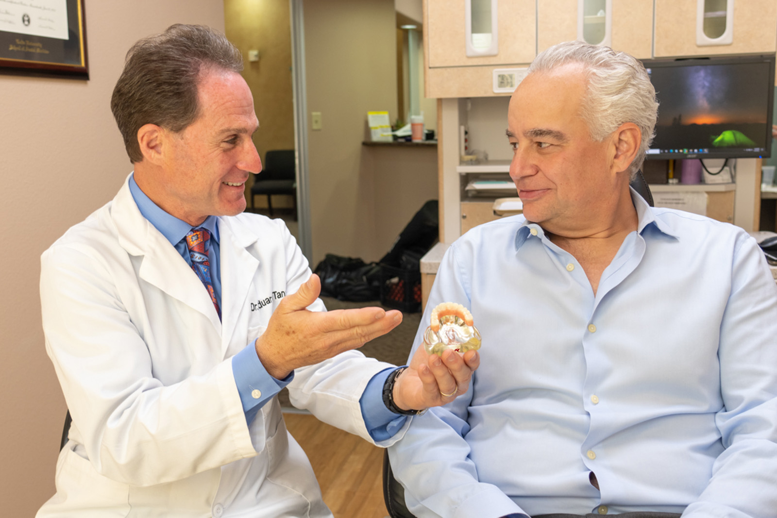 Dr. Tanur speaks to a patient regarding a teeth model