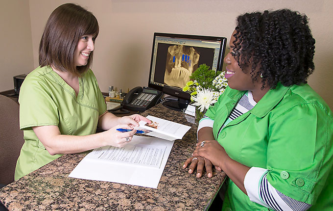 Dental receptionist showing pamphlet to a patient